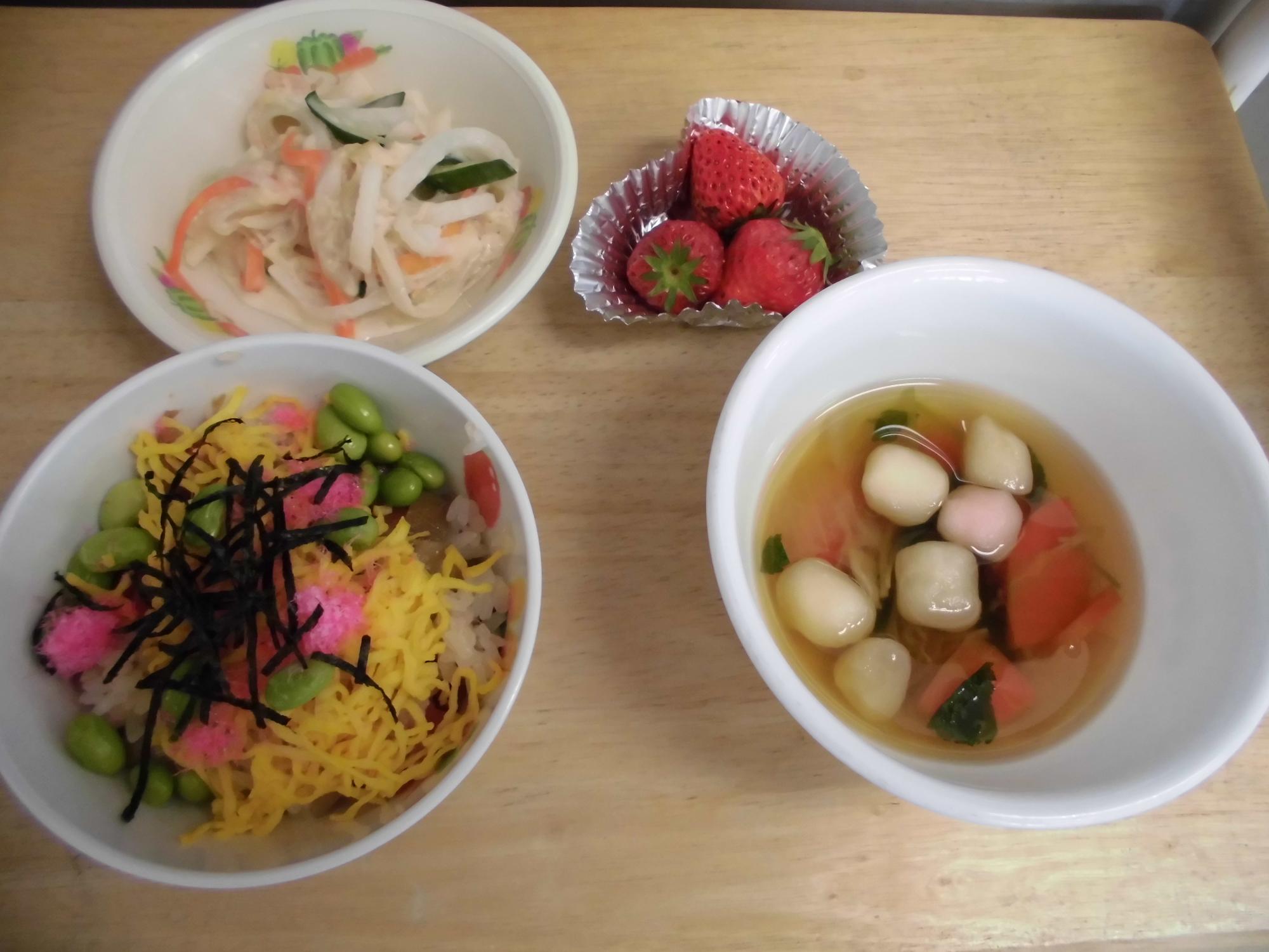 ちらし寿司、大根とにんじんのサラダ、すまし汁、イチゴの並んでいる給食の写真